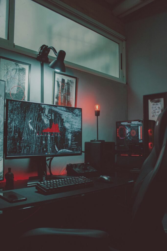 Stylish gaming setup featuring a monitor, keyboard, and illuminated PC in a cozy room with red LED lighting.