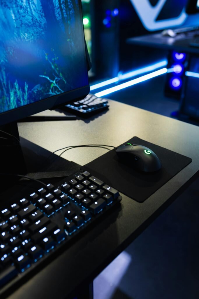 Modern gaming station with an LED-lit keyboard and high-resolution monitor in a dark room.