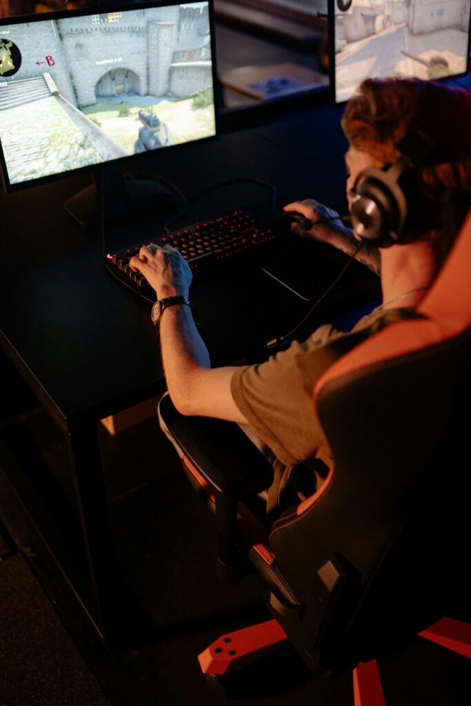Gamer immersed in video game using PC setup with headphones, indoors at night.